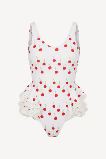 White swimsuit with red cherry pattern and ruffled bottom on a white background