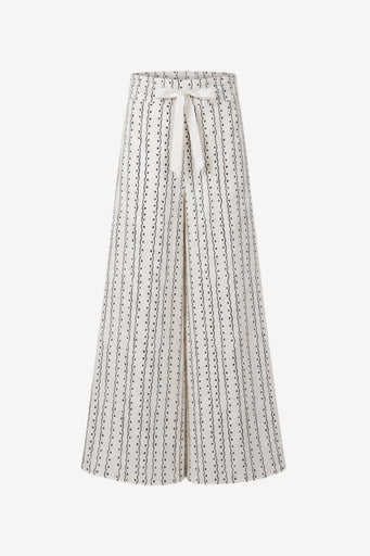 A high-waisted, wide-leg pleated skirt in cream with a black dotted vertical stripe pattern and a matching cream tie belt at the waist, shown against a plain light background.