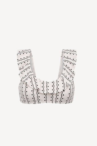 An off-white ruffled bikini top with black wavy line and dot patterns, featuring wide shoulder straps, shown against a plain light grey background.