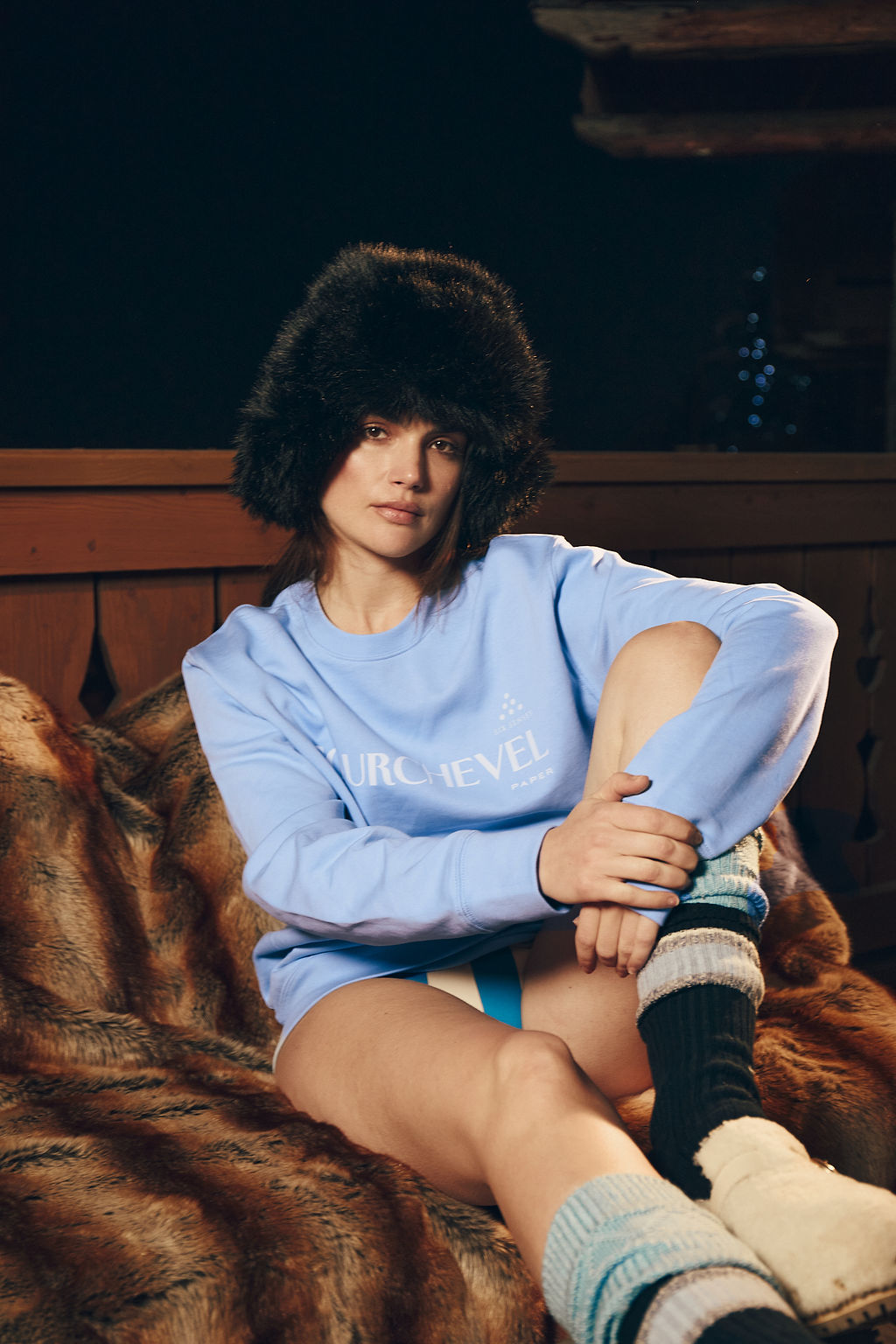 Woman wearing The Six Senses Courchevel blue sweatshirt sitting on a fur seat