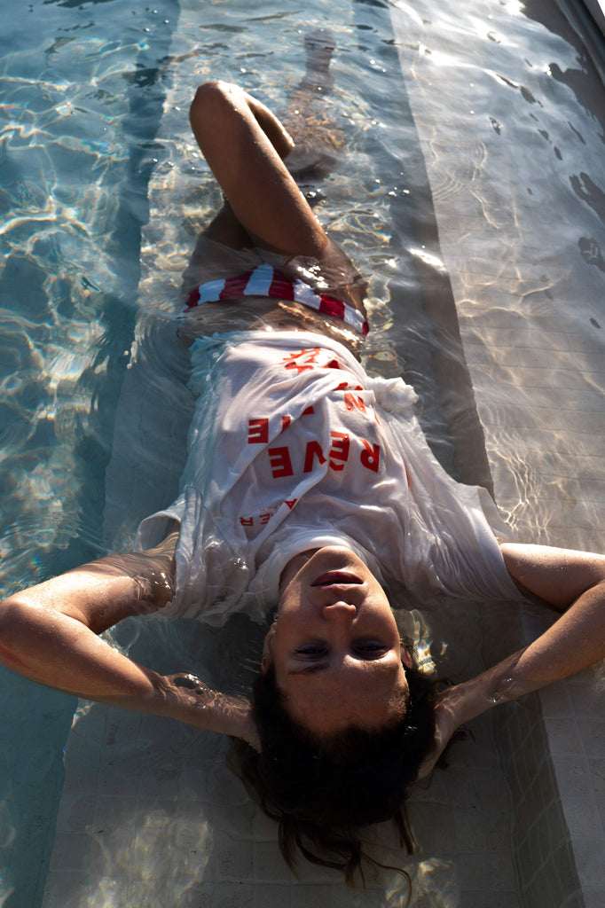 Woman lying in a pool, wearing low-rise red and ivory striped bikini bottoms
