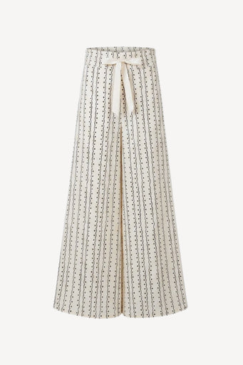 A high-waisted, wide-leg pleated skirt in cream with a black dotted vertical stripe pattern and a matching cream tie belt at the waist, shown against a plain light background.