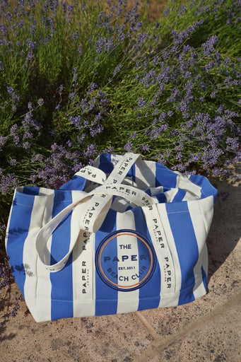 Blue and white striped tote bag with 'The Paper Beach Club' logo with lavender in the background