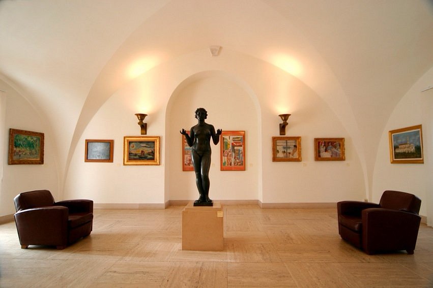 Inside gallery space showing a stature and paintings on the wall.