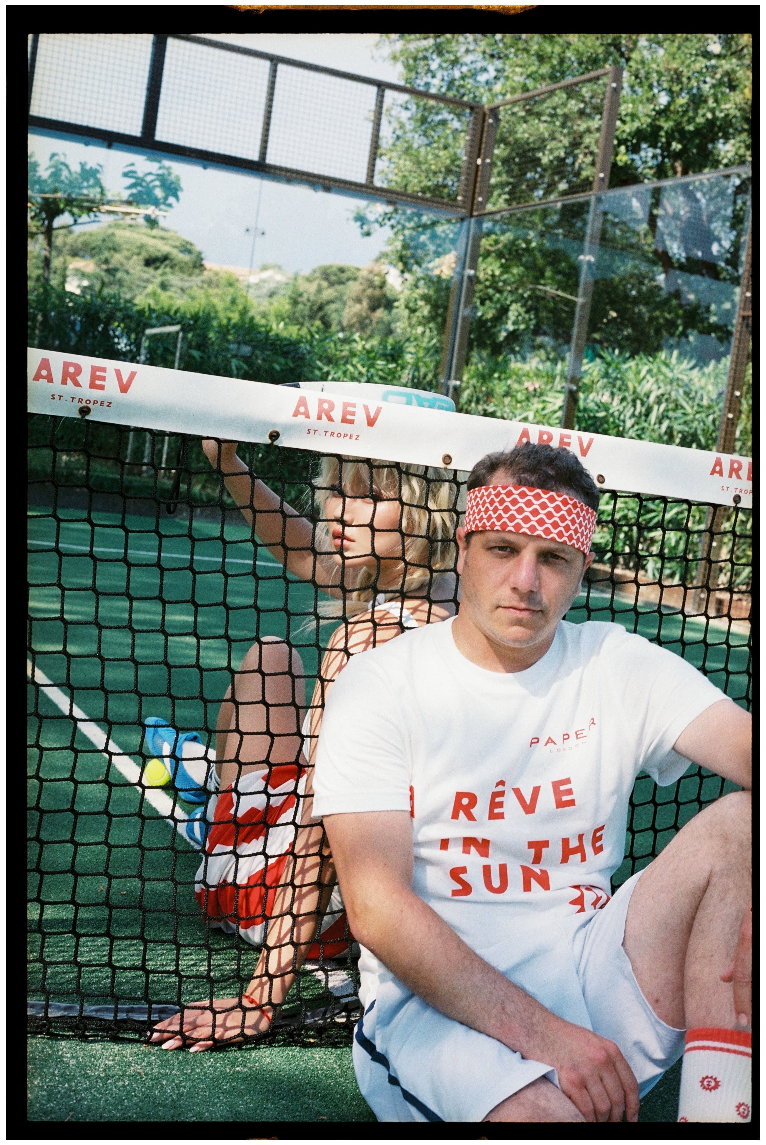 Man and woman sitting on a padel court in sportswear.